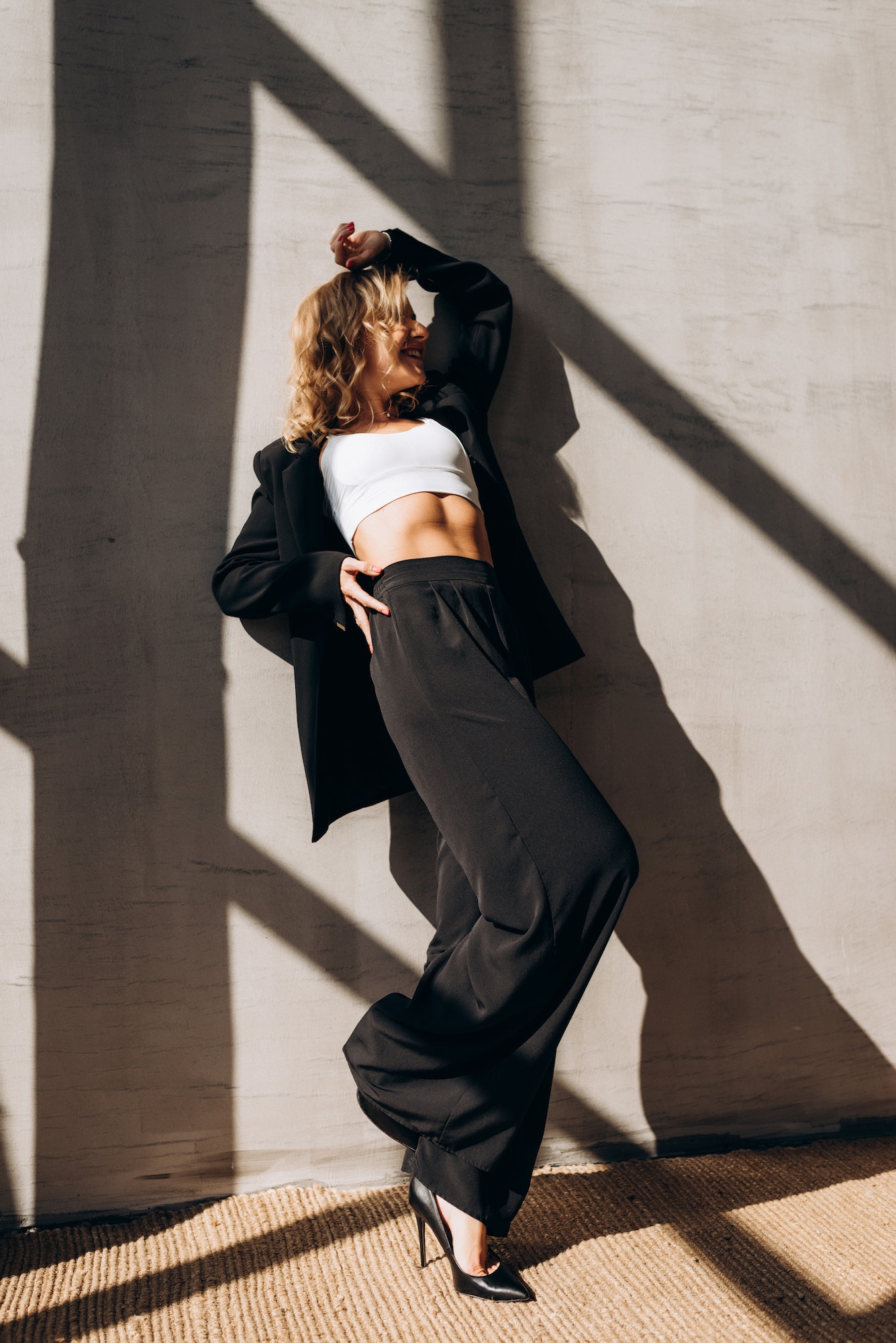 A young slender woman in a black trouser suit posing in the sunlight